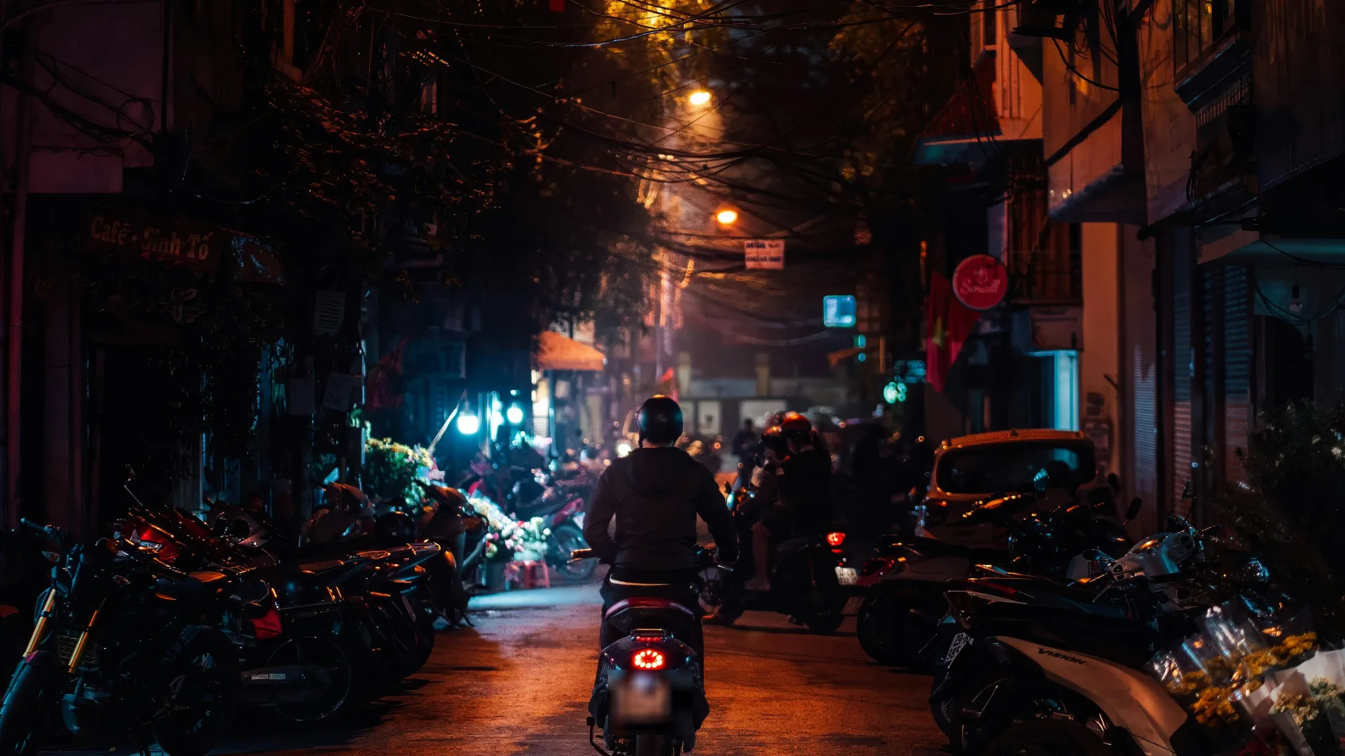 Một con phố nhỏ trong Phố Cổ Hà Nội buổi tối, đèn lồng đỏ treo cao, xe máy đỗ hai bên