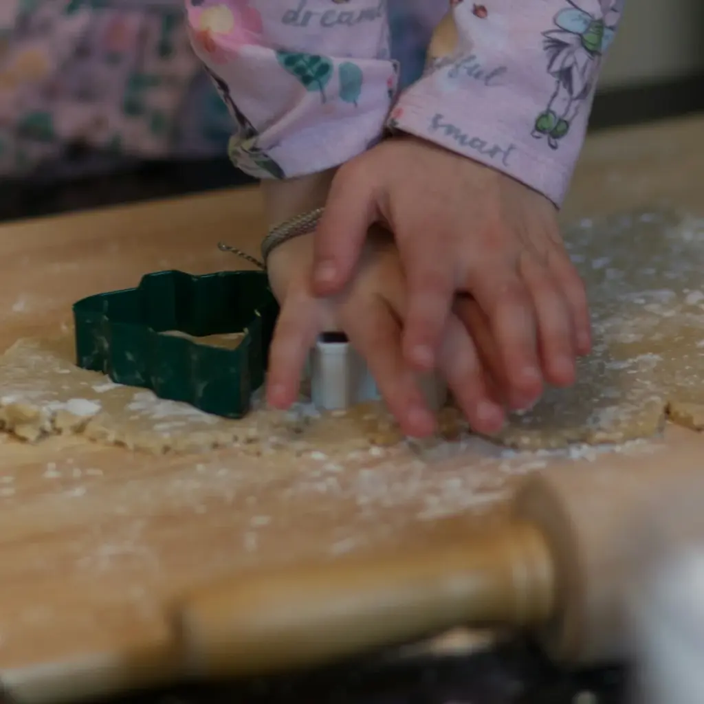 Bàn tay bé ấn khuôn cắt bánh quy trong giờ làm bánh, một hoạt động khi gửi bé ở Kids Club